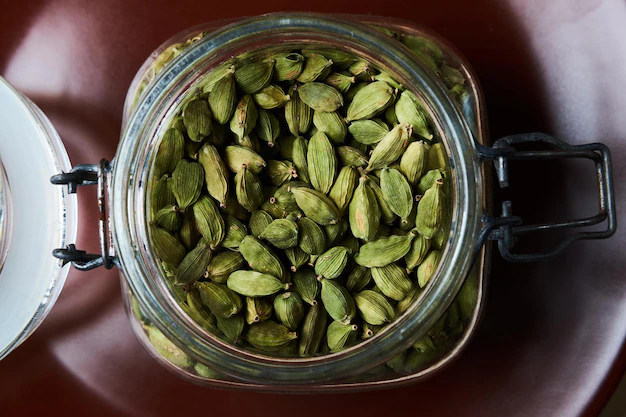 فوائد الهيل الصحية 2 closeup proto glass jar full green cardamom pods brown plate top view 613910 21738