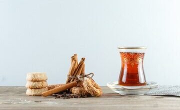 cinnamon sticks with biscuits cloves glass tea placemat side view wooden white wall 176474 6016