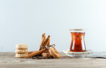 cinnamon sticks with biscuits cloves glass tea placemat side view wooden white wall 176474 6016